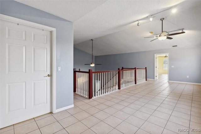 spare room with light tile patterned floors, ceiling fan, baseboards, and vaulted ceiling