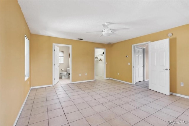 unfurnished room with ceiling fan, light tile patterned floors, visible vents, and baseboards