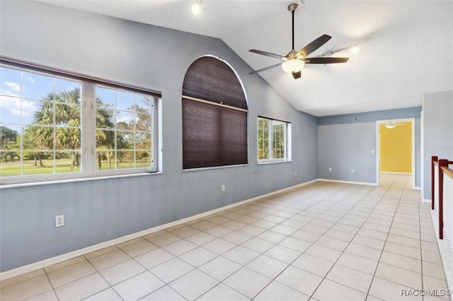 tiled spare room with lofted ceiling, a healthy amount of sunlight, ceiling fan, and baseboards