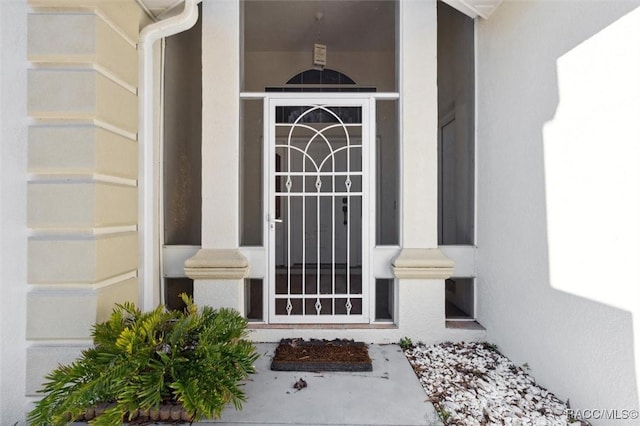 view of exterior entry with an attached garage and stucco siding