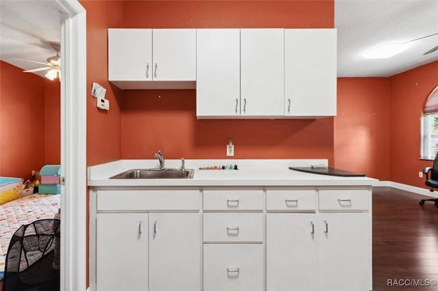 kitchen with dark wood-style floors, light countertops, a sink, and white cabinets