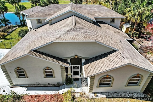 mediterranean / spanish-style house featuring roof with shingles, fence, and stucco siding