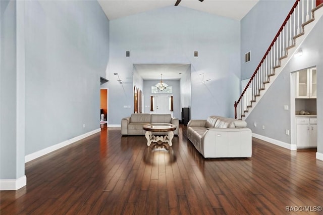 living area featuring stairs, ceiling fan with notable chandelier, hardwood / wood-style flooring, and baseboards