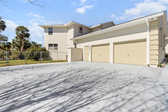 view of front of house with an attached garage, fence, driveway, a gate, and stucco siding