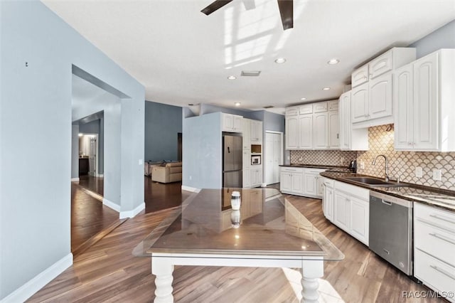 kitchen with a sink, white cabinets, appliances with stainless steel finishes, decorative backsplash, and dark countertops