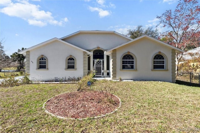 ranch-style house with a front yard, fence, and stucco siding