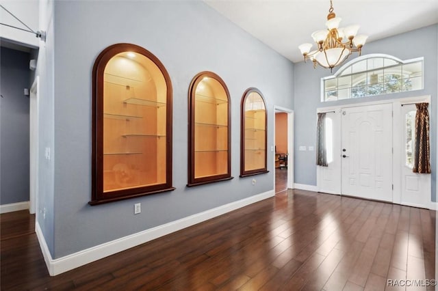 foyer with baseboards, dark wood finished floors, and a notable chandelier