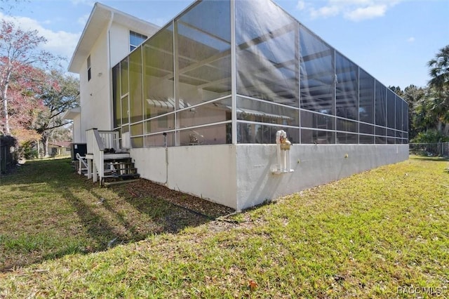 view of side of property featuring a lawn and a lanai