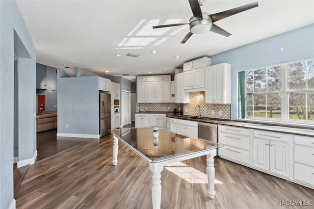 kitchen featuring white cabinets, appliances with stainless steel finishes, decorative backsplash, and a sink