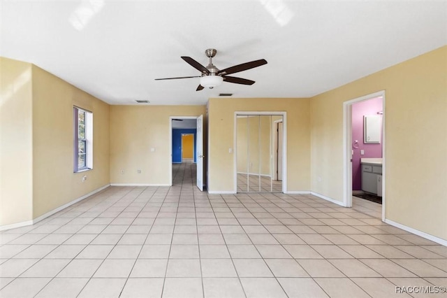 empty room featuring visible vents, light tile patterned floors, a ceiling fan, and baseboards