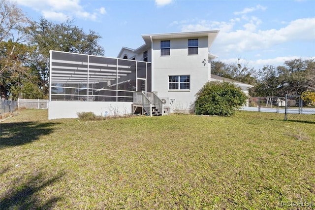 back of property with glass enclosure, stucco siding, fence, and a yard