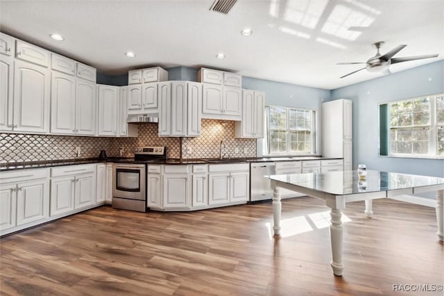 kitchen featuring stainless steel appliances, a sink, visible vents, decorative backsplash, and dark countertops