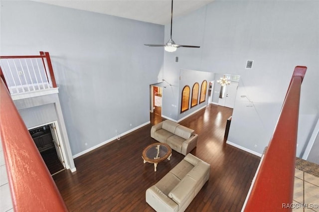 living area with baseboards, high vaulted ceiling, wood finished floors, and a glass covered fireplace