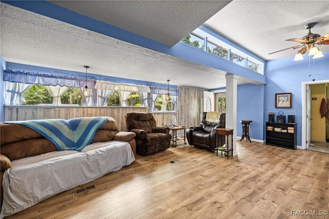 22535 SW 117th St, Dunnellon, FL 34431 - living room featuring a textured ceiling, light wood-style floors, ornate columns, ceiling fan, and healthy amount of natural light