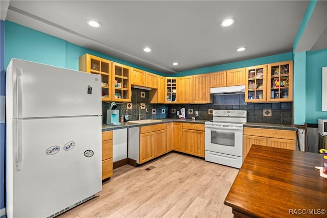 22535 SW 117th St, Dunnellon, FL 34431 - kitchen with white appliances, under cabinet range hood, glass insert cabinets, light wood-style flooring, and decorative backsplash