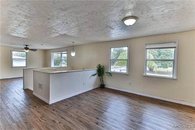 kitchen with ceiling fan, dark wood-type flooring, hanging light fixtures, and kitchen peninsula