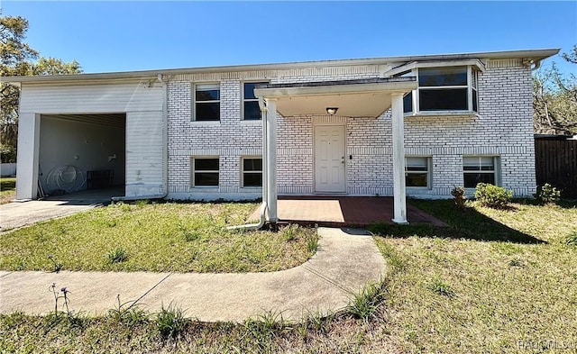 view of front of house with brick siding, concrete driveway, and a front yard