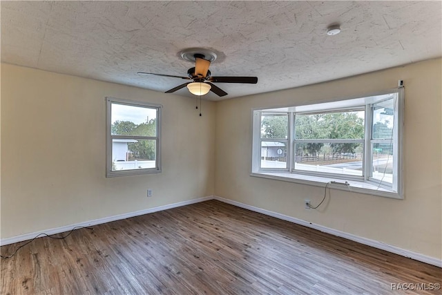 empty room with ceiling fan, wood-type flooring, and a textured ceiling