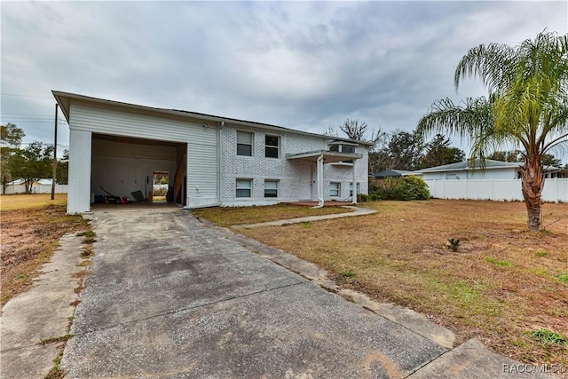 split foyer home with a front lawn, fence, concrete driveway, a garage, and brick siding