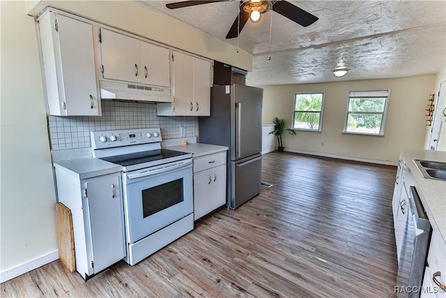 kitchen with white cabinetry, stainless steel appliances, backsplash, light wood-type flooring, and ceiling fan