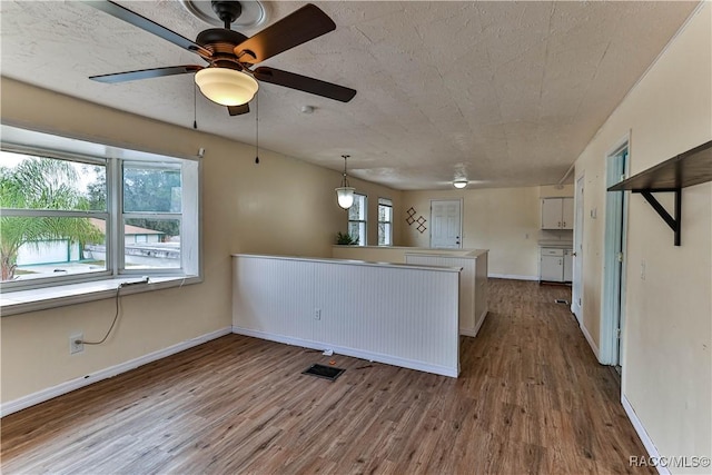 kitchen with decorative light fixtures, kitchen peninsula, white cabinetry, and hardwood / wood-style flooring