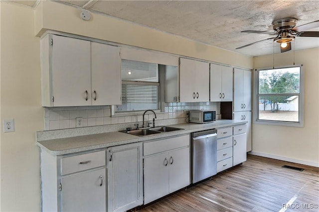 kitchen featuring white cabinetry, light hardwood / wood-style floors, decorative backsplash, stainless steel dishwasher, and sink