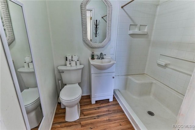 bathroom with a shower, hardwood / wood-style floors, toilet, and vanity