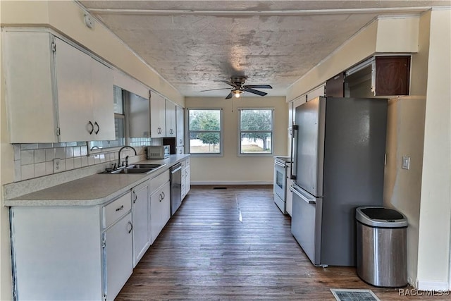 kitchen featuring white cabinetry, stainless steel appliances, tasteful backsplash, sink, and ceiling fan