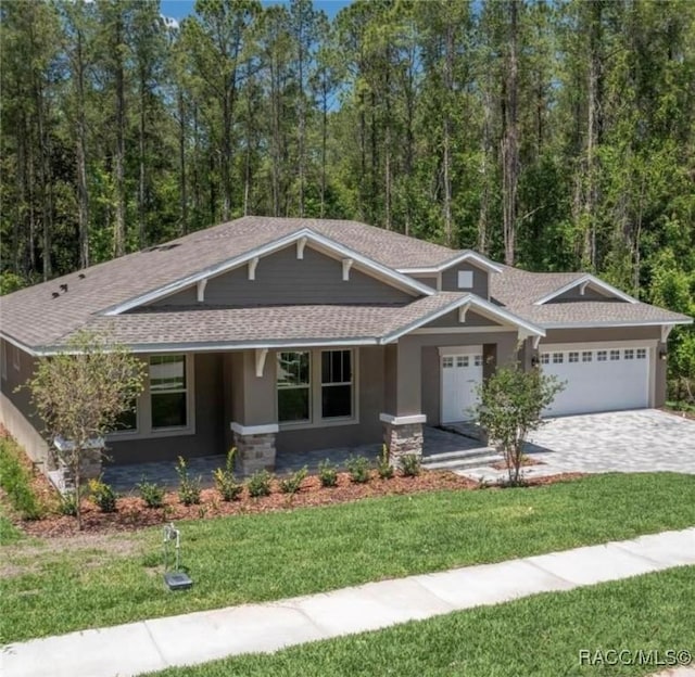 craftsman inspired home featuring covered porch, a garage, and a front lawn