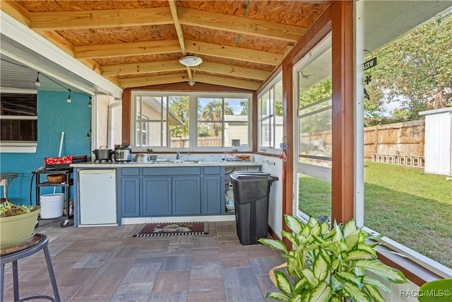 unfurnished sunroom featuring lofted ceiling and sink