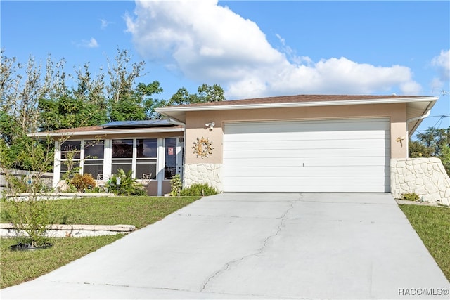 ranch-style home with a front yard, solar panels, and a garage