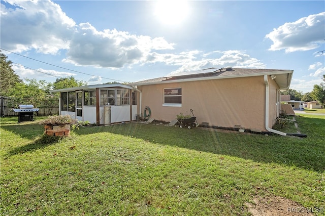 rear view of property featuring a lawn and a sunroom