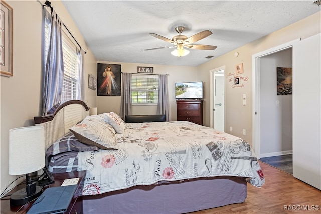 bedroom with ceiling fan, dark hardwood / wood-style flooring, and a textured ceiling