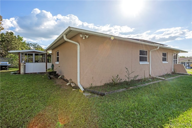 view of side of home with a sunroom and a yard