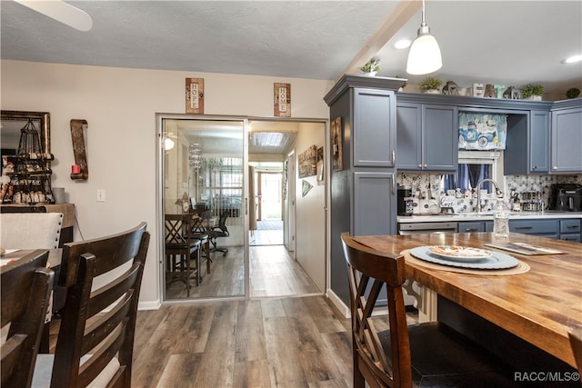 kitchen with sink, hanging light fixtures, dark hardwood / wood-style floors, butcher block countertops, and decorative backsplash