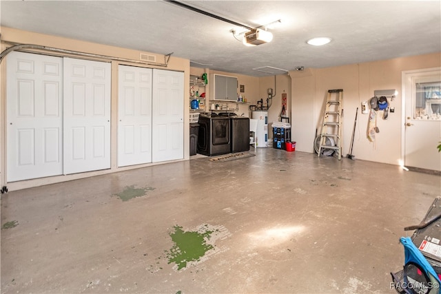 garage with electric water heater, washer and clothes dryer, and a garage door opener