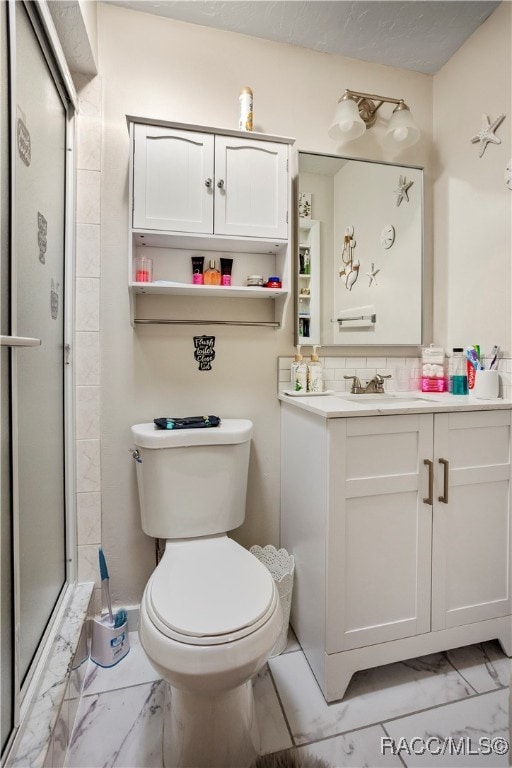 bathroom featuring vanity, toilet, a shower with shower door, and backsplash