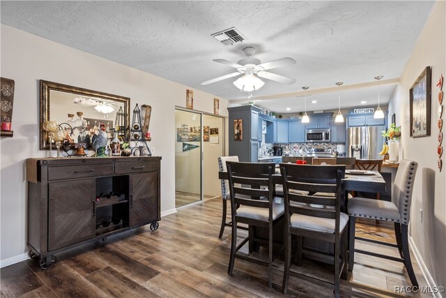 dining room with a textured ceiling, hardwood / wood-style flooring, ceiling fan, and a healthy amount of sunlight