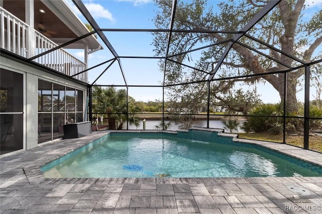 view of pool with a lanai, ceiling fan, a water view, and a patio