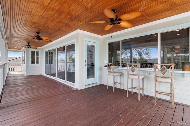 deck featuring ceiling fan and exterior bar