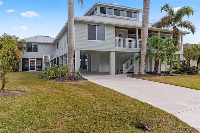 raised beach house featuring a front lawn and a carport