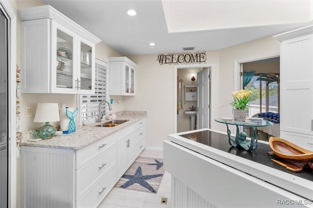 kitchen featuring white cabinets, sink, and light stone counters