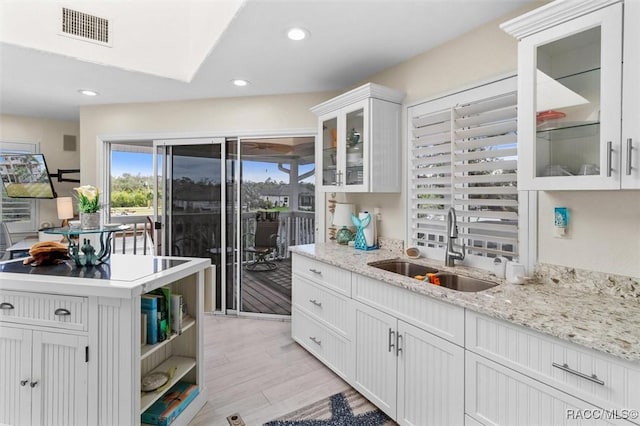 kitchen featuring white cabinetry, light hardwood / wood-style flooring, light stone counters, and sink