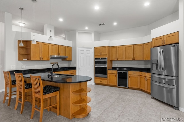 kitchen with appliances with stainless steel finishes, a towering ceiling, decorative light fixtures, sink, and wine cooler