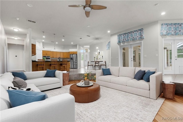 living room with light hardwood / wood-style flooring, french doors, and ceiling fan