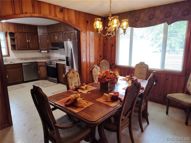 dining room featuring a chandelier and wooden walls