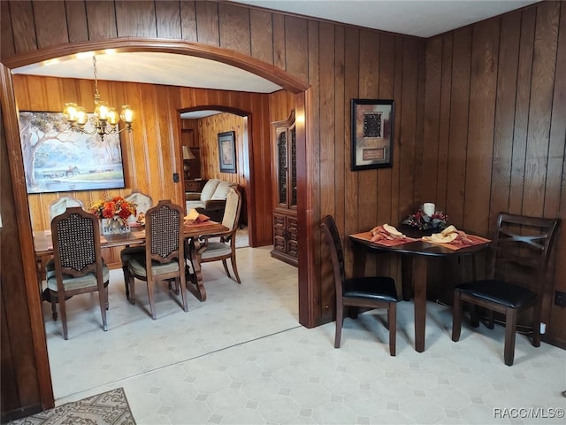 dining room with wood walls and a chandelier