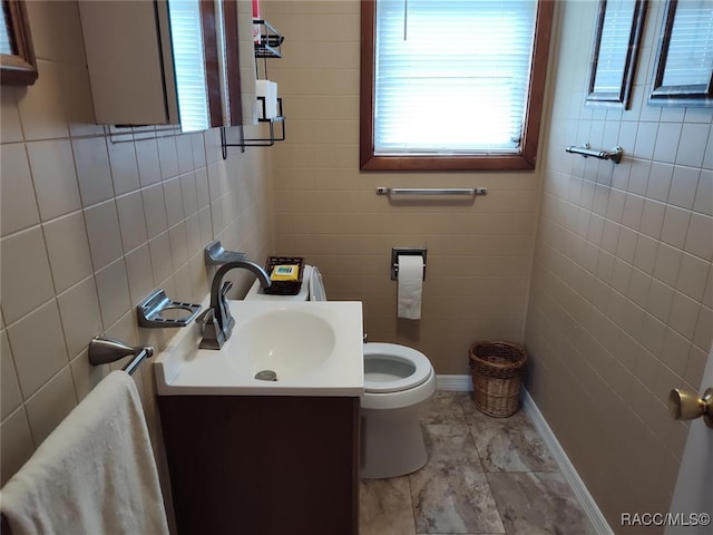 bathroom featuring vanity, toilet, and tile walls