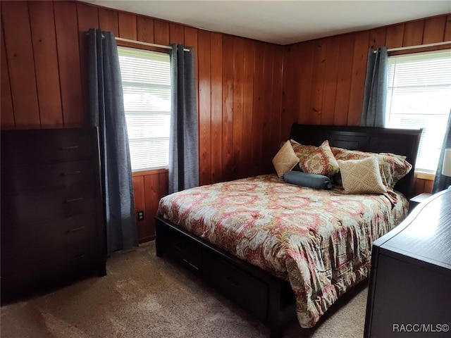 carpeted bedroom featuring multiple windows and wood walls