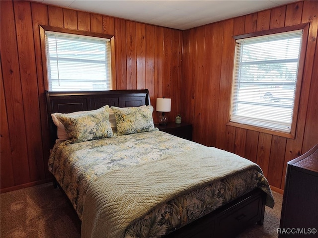 bedroom with dark carpet and wooden walls